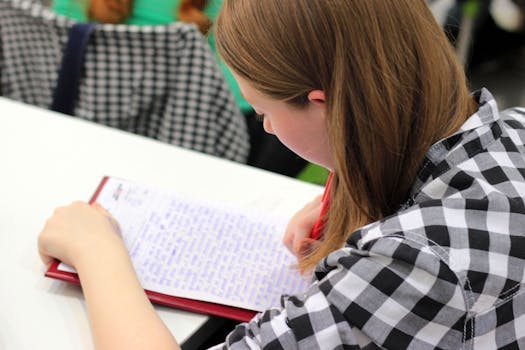pexels-photo-267491-267491 A young student writing in a notebook during a study session indoors.